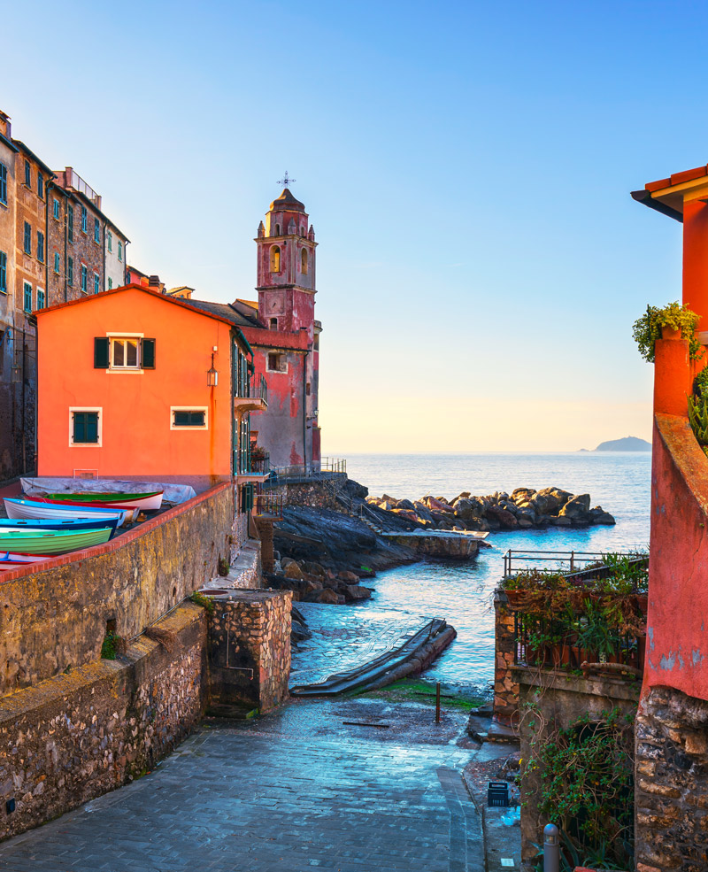 Calle con iglesia al fondo y botes en Cinque Terre
